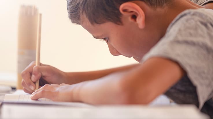 boy holding a pencil and working on school work up close