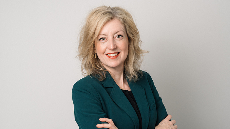 a portrait of a woman wearing a teal jacket blazer with a nice smile and crossing her arms