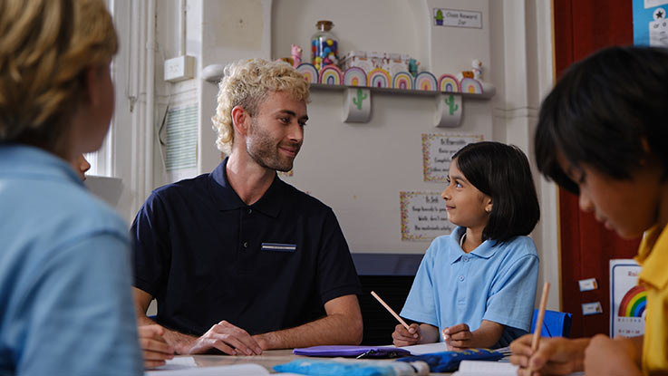 Gil sitting in classroom with adult