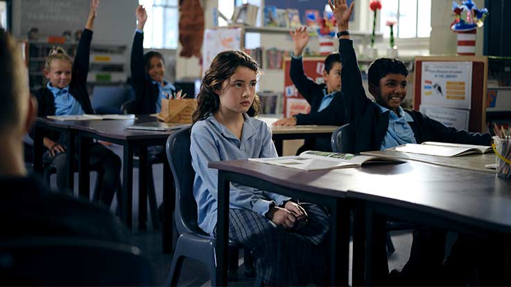 Lucy sitting at a desk in classroom