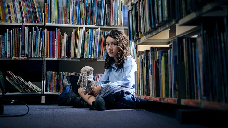 Lucy sitting among bookshelves in a library