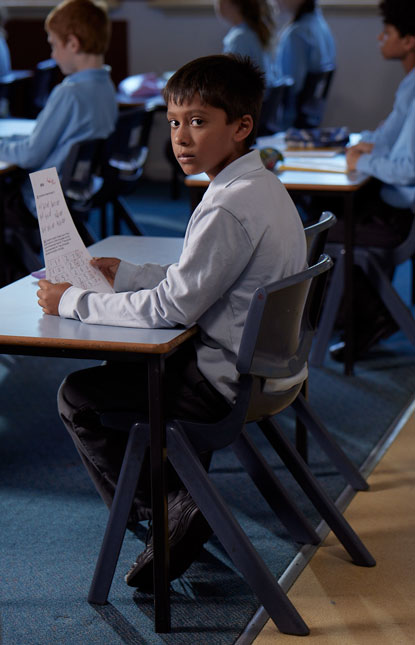 young boy sitting at desk in classroom