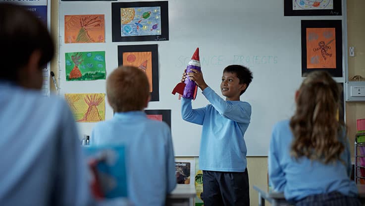 student showing rocket for show and tell in classroom science project