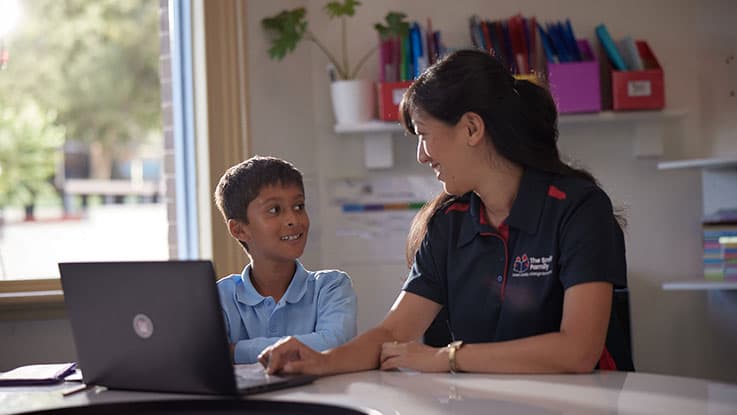 student receiving school help on laptop from childrens charity worker