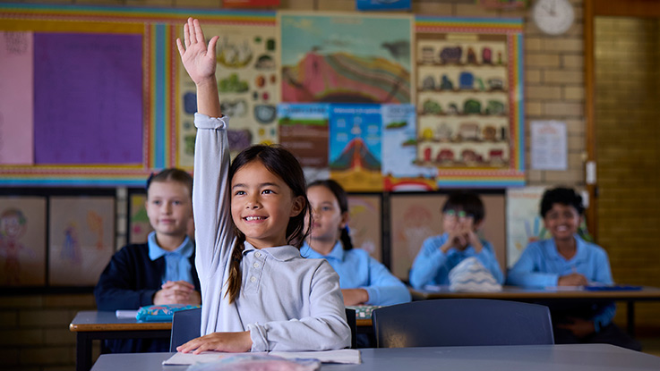 a school girl raising her hand in a classroom