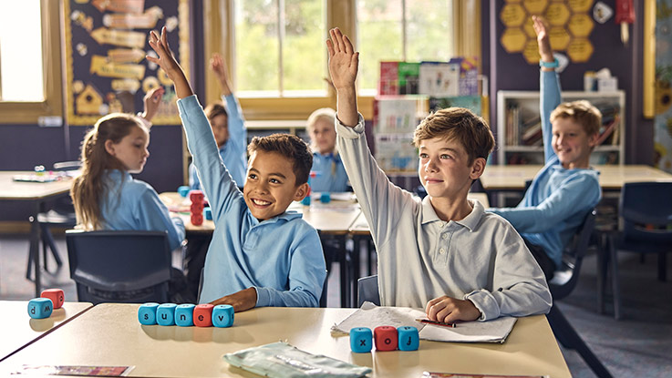 school kids in the classroom with their hand up