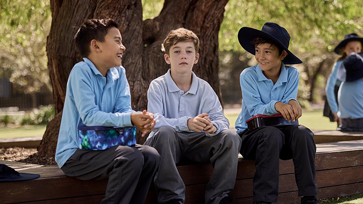 a school boy sitting in the school yard with his friends