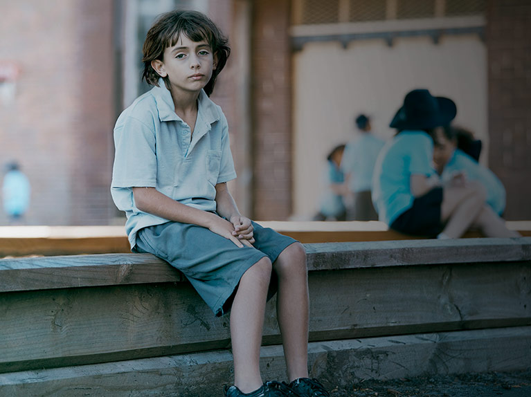 Zack looking sad sitting on playground fence