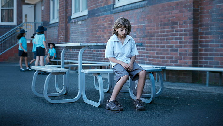 Zack looking sad at table in playground