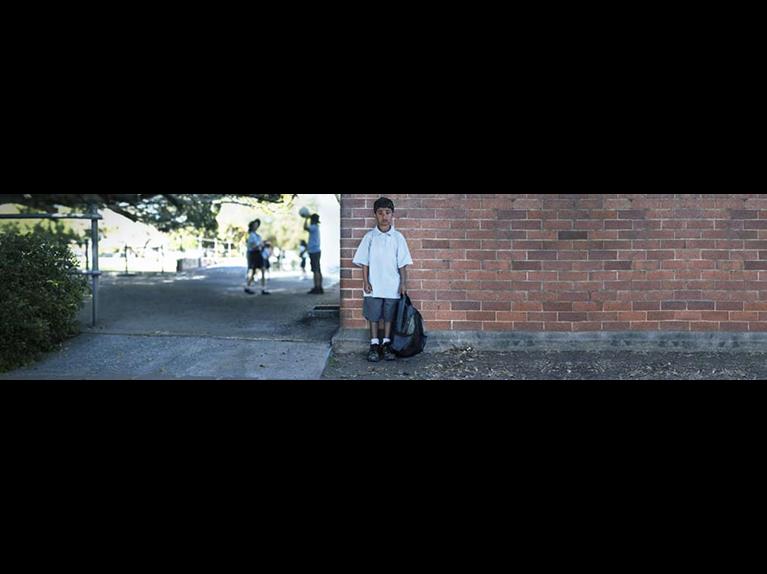 School boy standing in front of school building