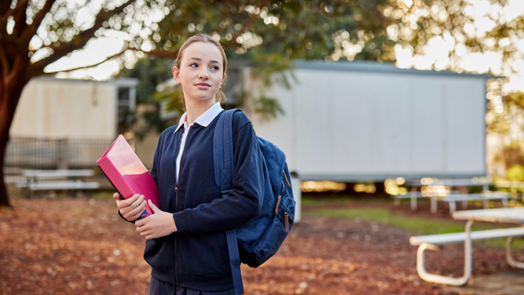 Student holding pink folder looking over shoulder