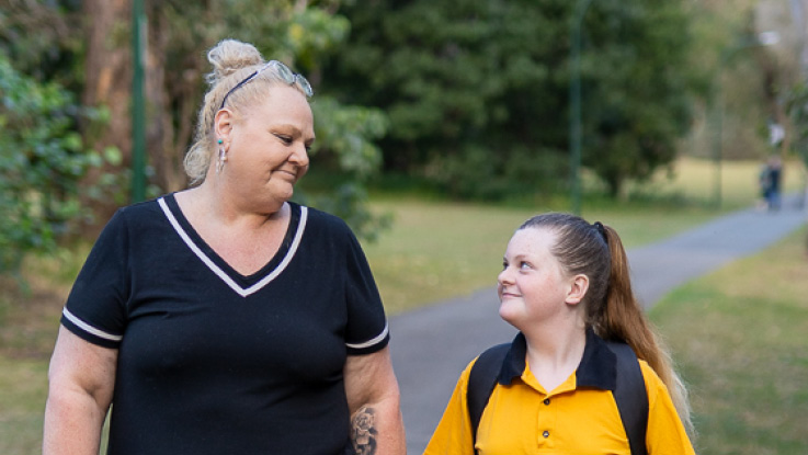 a mother looking onto her daughter who is wearing her school uniform and carrying a backpack