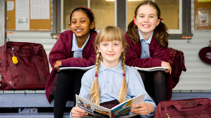 Three girls sitting on steps with books