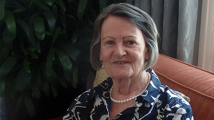 a elderly lady looking content towards the camera wearing a blue and white patterned top