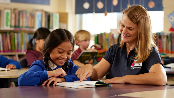 Teacher with student sitting at classroom desk