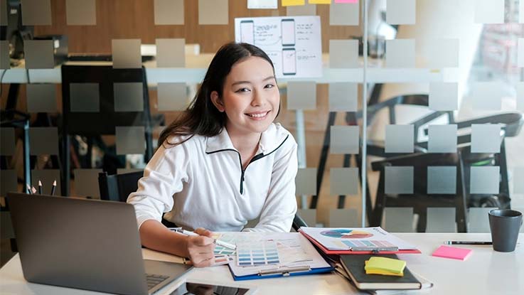 Woman working at desk with laptop and books