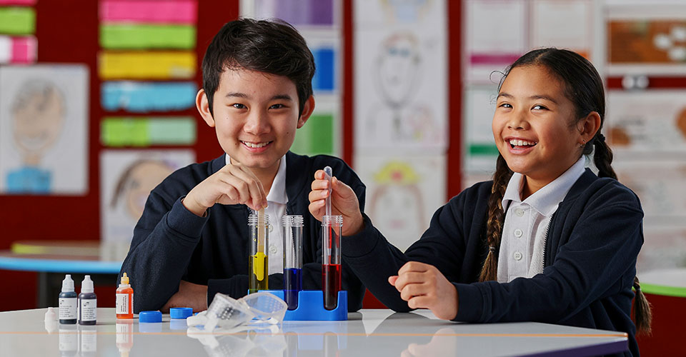 two school kids doing a science activity smiling