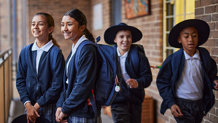 students standing in a school hallway looking outwards while other students run past