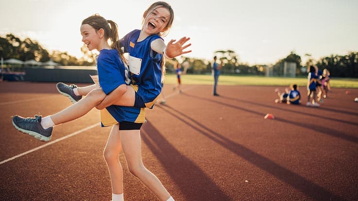 girl-carrying-another-girl-on-her-back-in-sportsfield