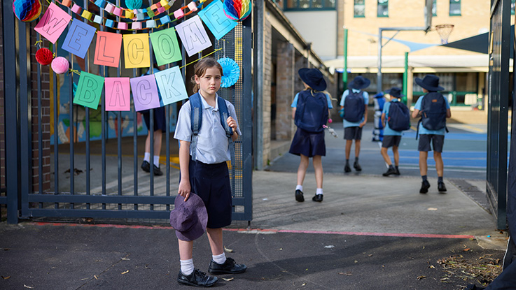 student standing at school gate looking at camera