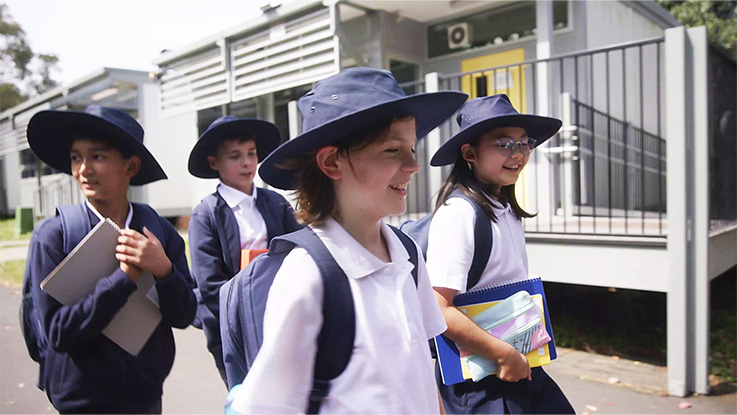 students walking in school grounds wearing school uniform