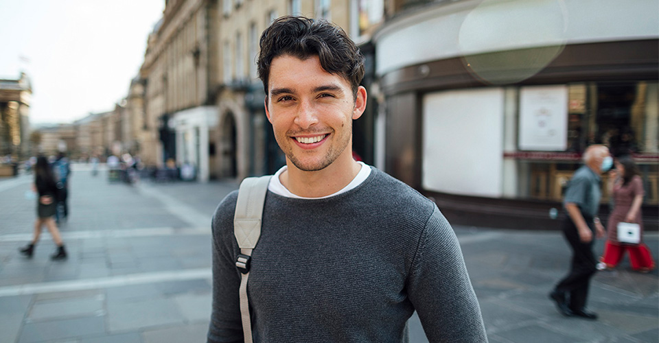male smiling wearing a grey sweater