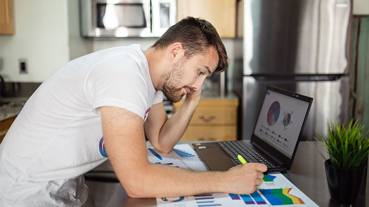 man sitting on a desk highlighting a page of graphs