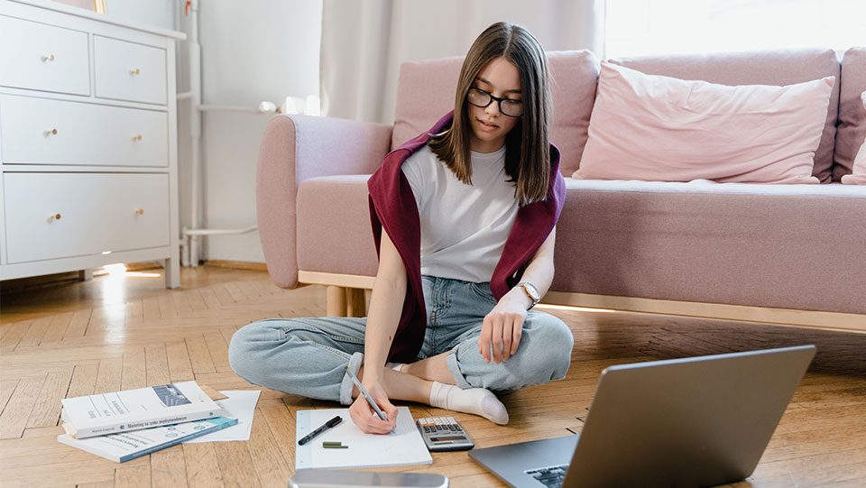 teen studying on the floor of her room