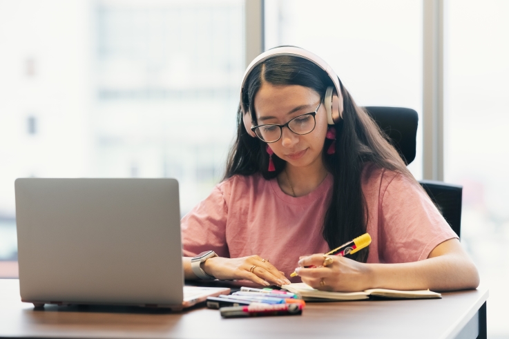 young girl taking notes with a laptop