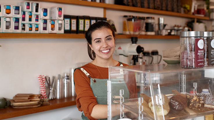 woman smiling standing behind a counter in a cafe