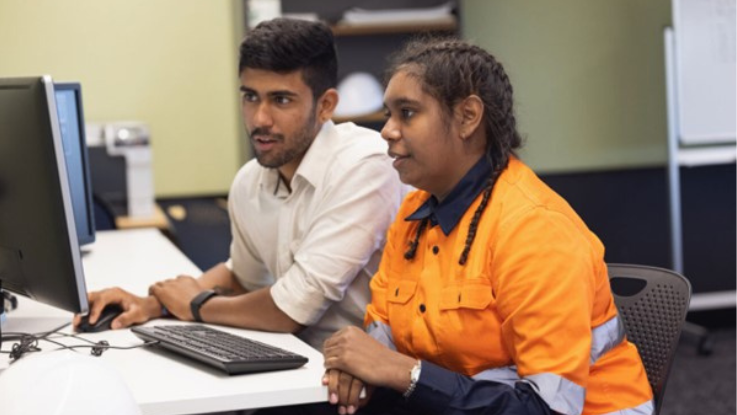 2 people, a male and female sitting at a computer desk
