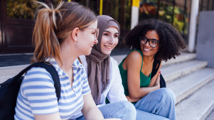 3 girls sitting on steps outside and smiling
