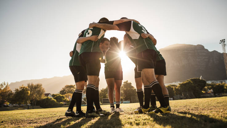 a sports team wearing green jerseys huddled up together in formation
