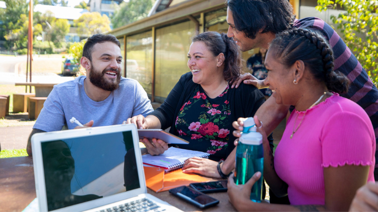 Students studying together with a mentor outdoors, representing supportive learning environments for young people.