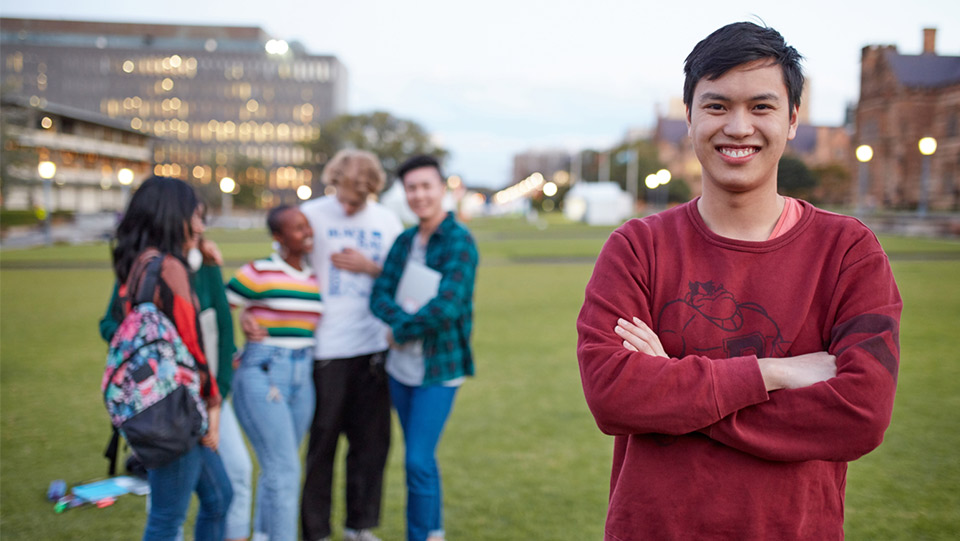 a group of students standing together on a field with a male student facing front on with a red sweater