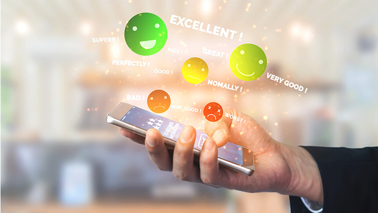a picture of a hand holding a smartphone with words and emojis floating above