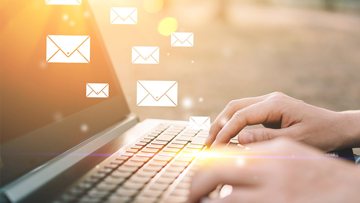 a person using a laptop with hovering images of envelopes