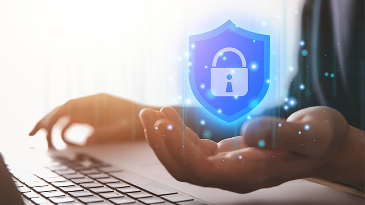 Hands using a laptop with a digital shield and padlock icon representing online security, privacy and data protection.