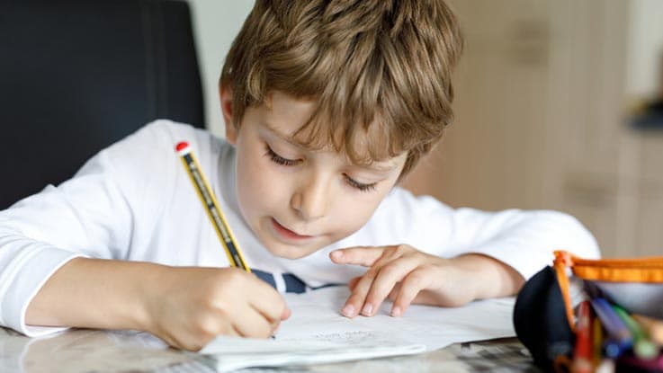 Young boy writing with a pencil on paper