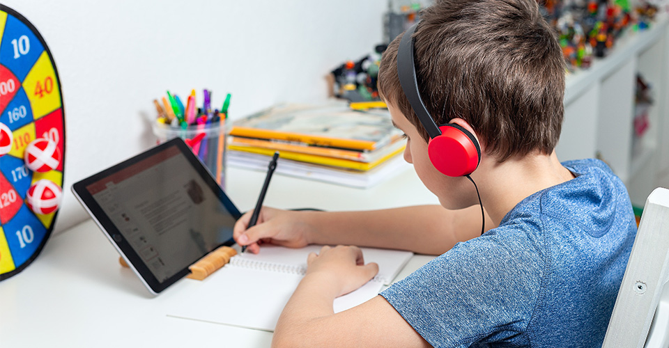 a child with headphones is using their tablet doing school work