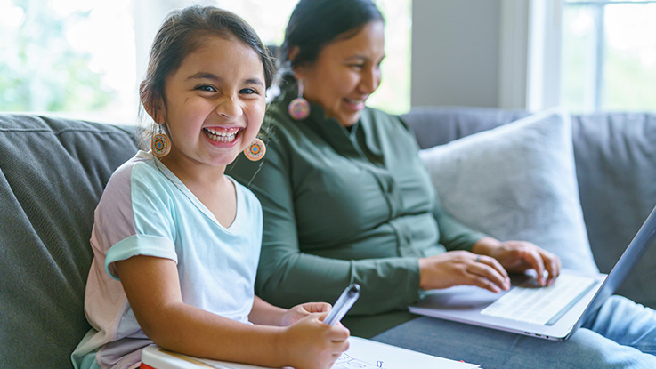 mother and daughter sitting on the couch together smiling