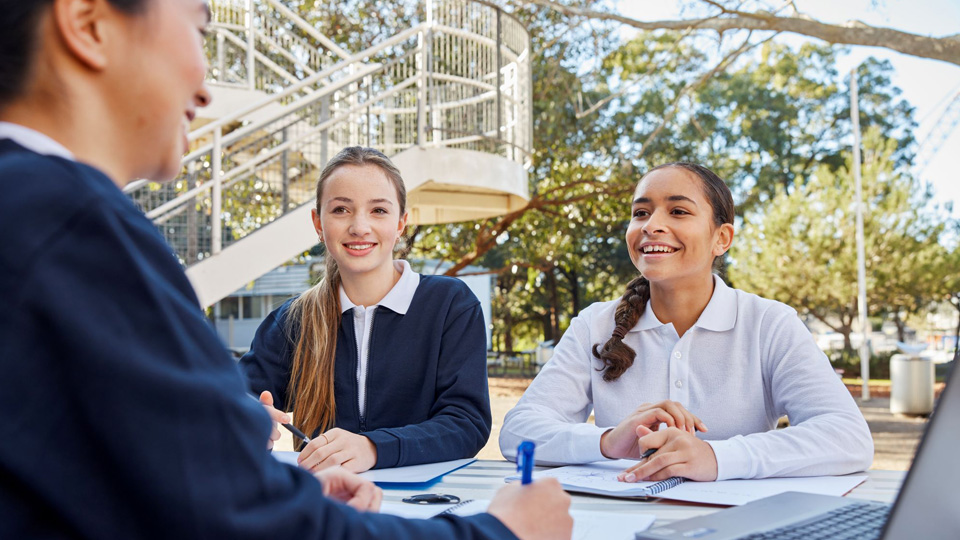 3 girls wearing school uniforms using the computer