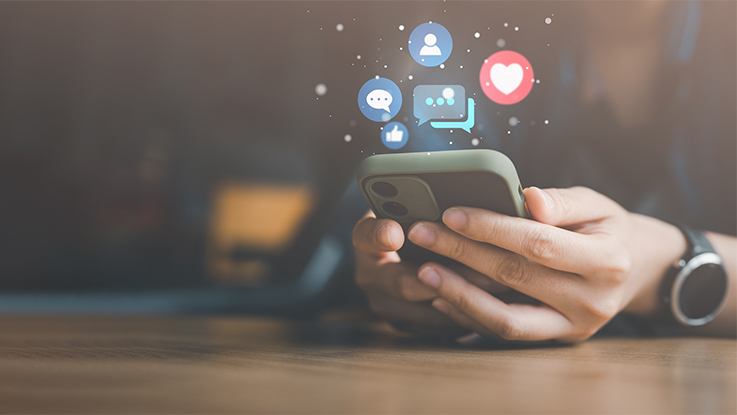 Hand holding a smartphone displaying social media and message icons.