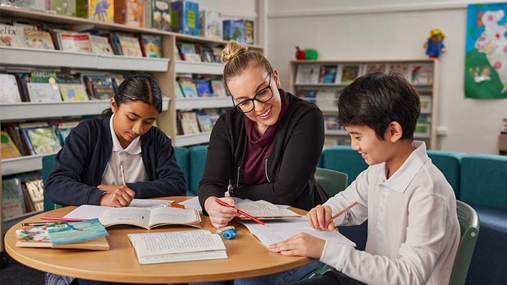 a family partnership coordinator helping two students in the library