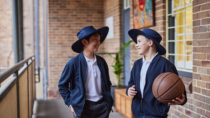 two school boys smiling each other in the classroom corridor