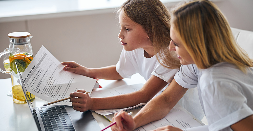 a mother helping her daughter with homework at home