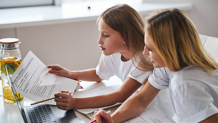 a mother is helping her young daughter with homework