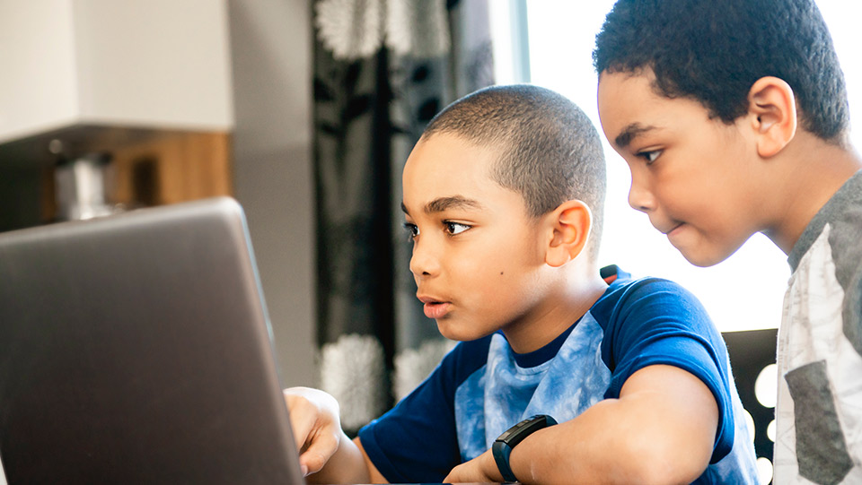 two boys viewing a laptop together
