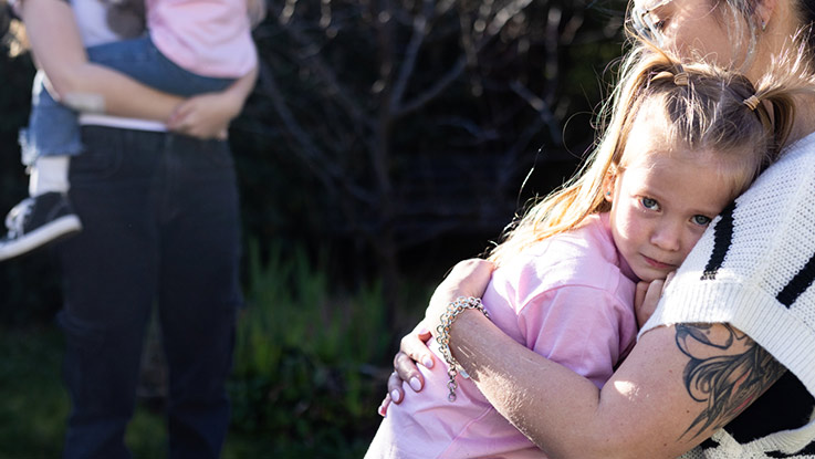 a young child is being hugged by her mother