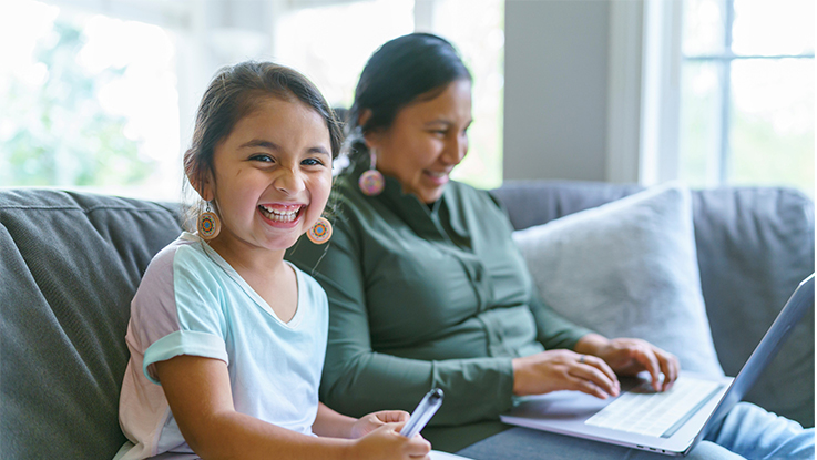 Mother and daughter on couch and mother is looking at a laptop